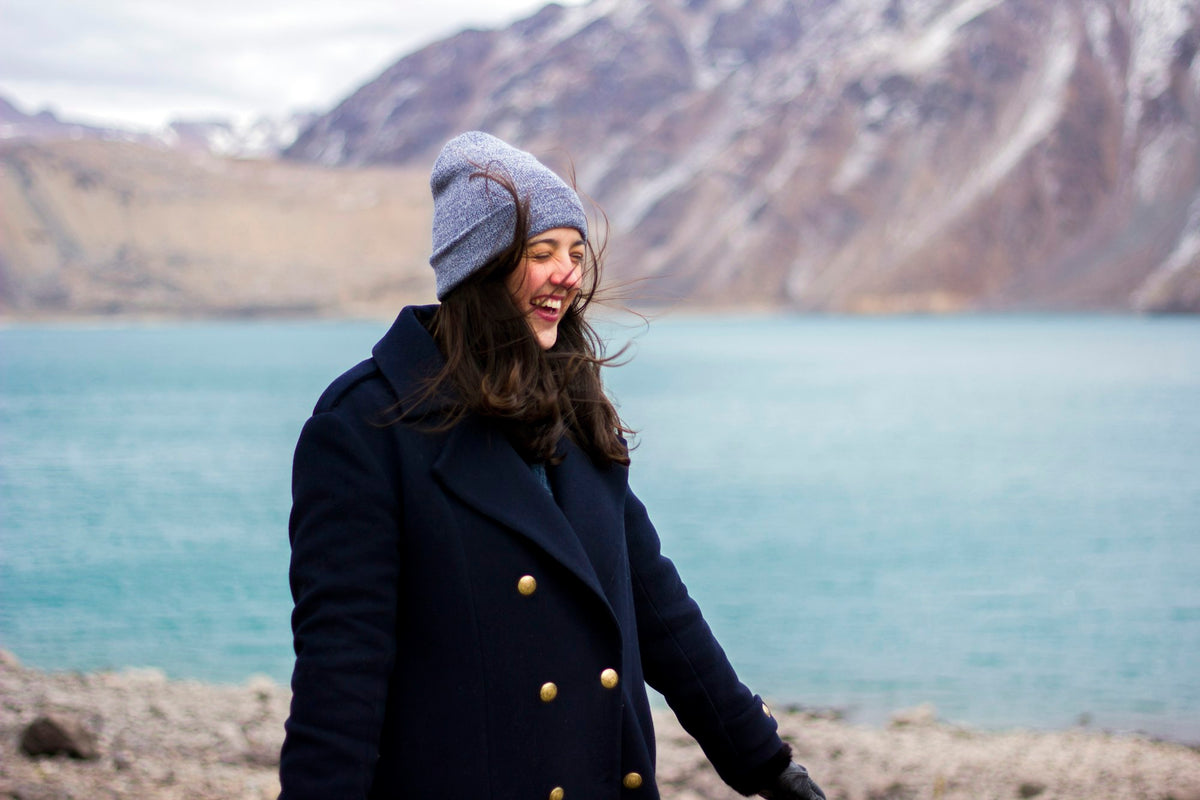 Happy woman wearing a winter coat by the water