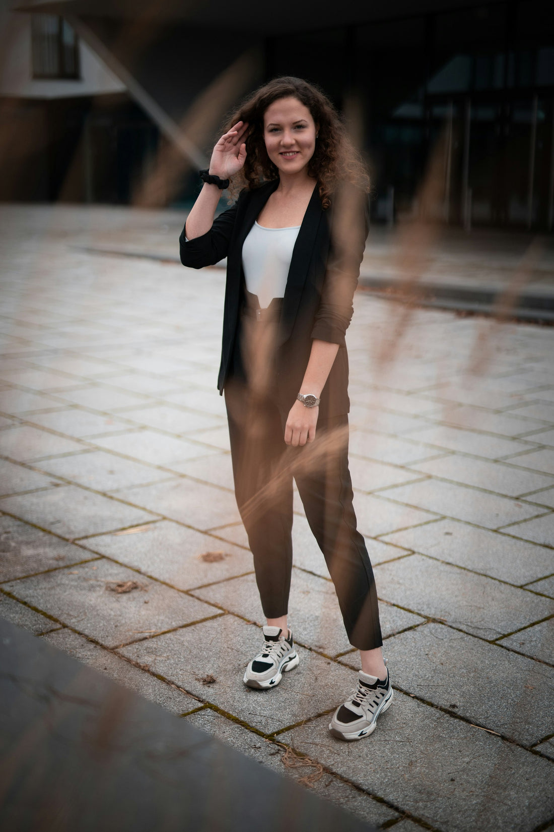Smiling woman in a blazer and brown trousers on the street