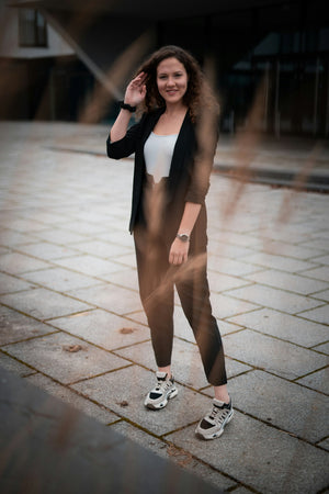 Smiling woman in a blazer and brown trousers on the street
